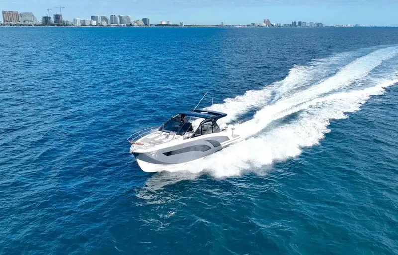 Slide: The Image of A 2025 Hanover 387 boat cruising on blue ocean waters with city skyline in background. - 7