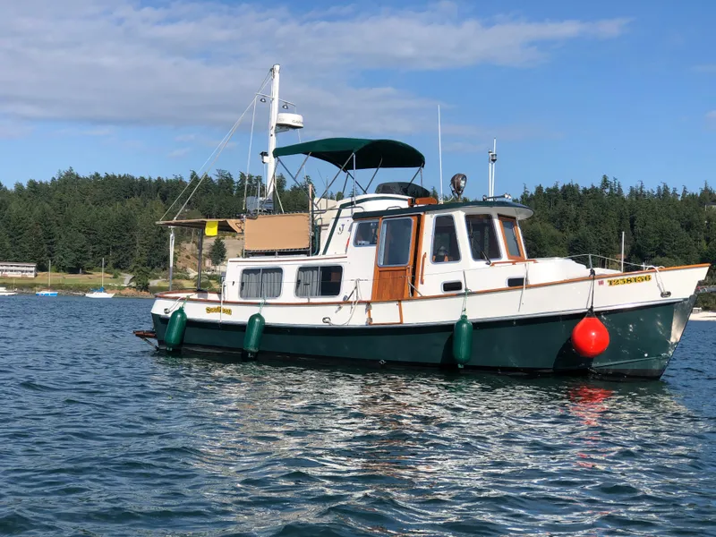 The Image of 1989 Eagle 32 Trawler boat on water, with forested shoreline in background. - 0