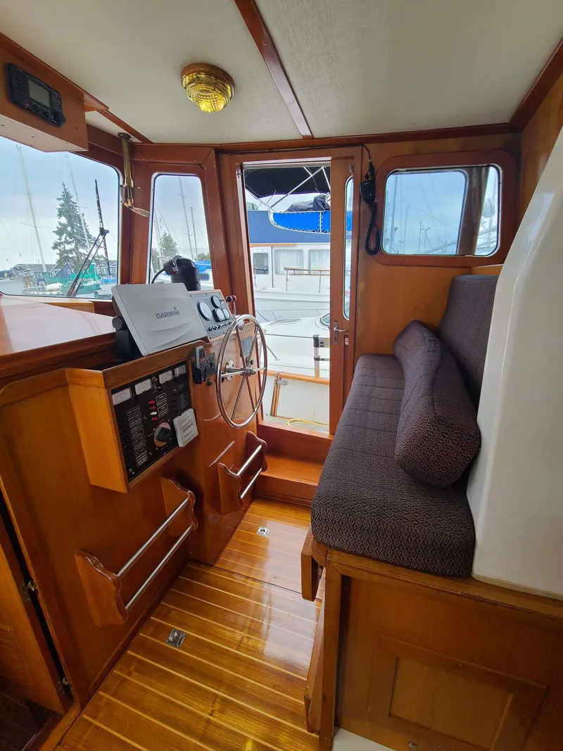 Slide: The Image of 1989 Eagle 32 Trawler interior with wooden helm, steering wheel, and cushioned seating. - 10
