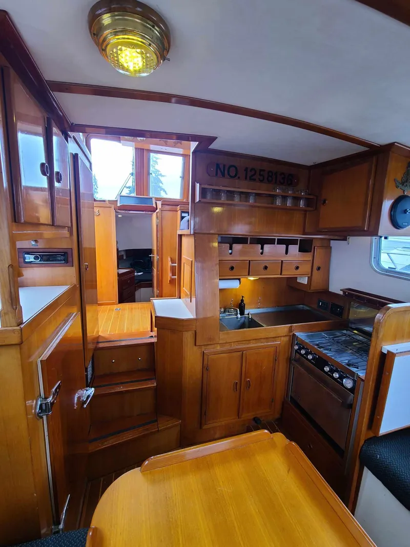 Slide: The Image of 1989 Eagle 32 Trawler interior with wooden cabinetry, kitchen, and dining area. - 14