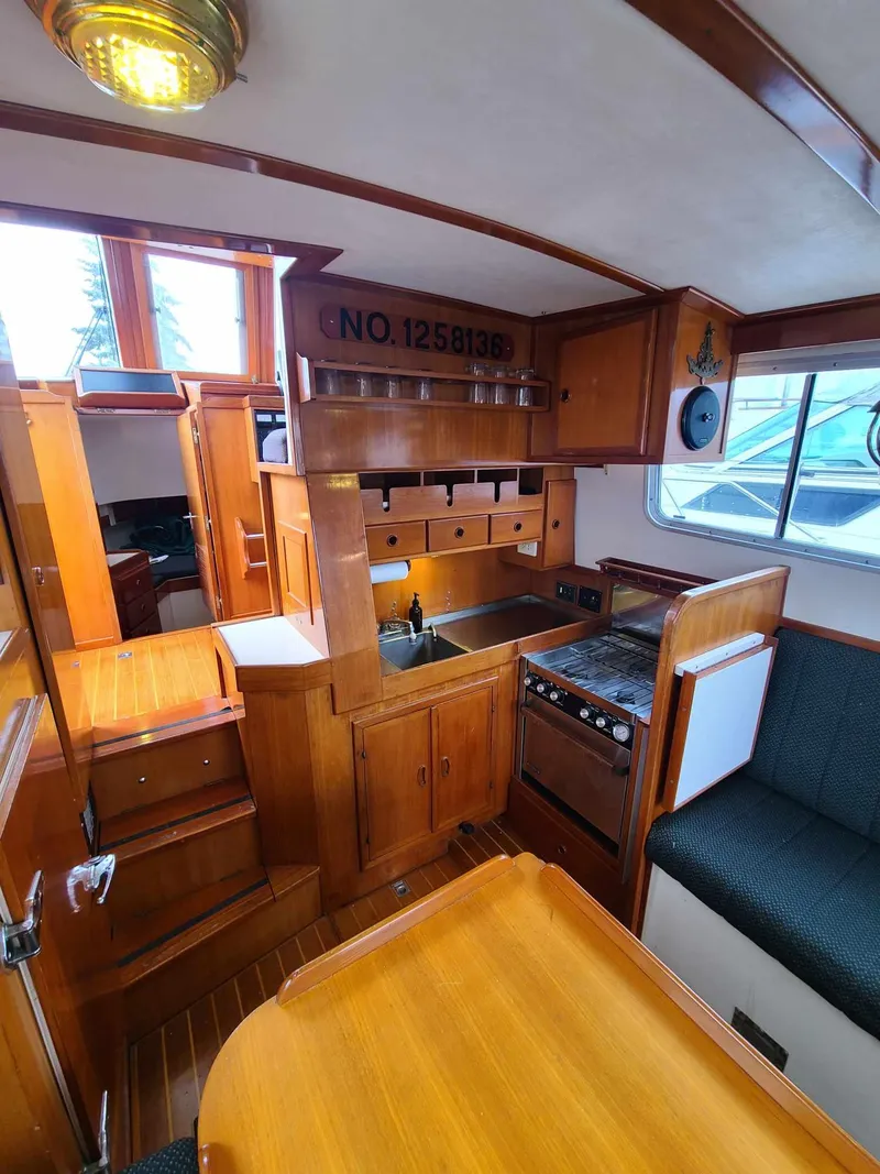 Slide: The Image of 1989 Eagle 32 Trawler interior with wooden cabinetry, kitchen, and seating area. - 16