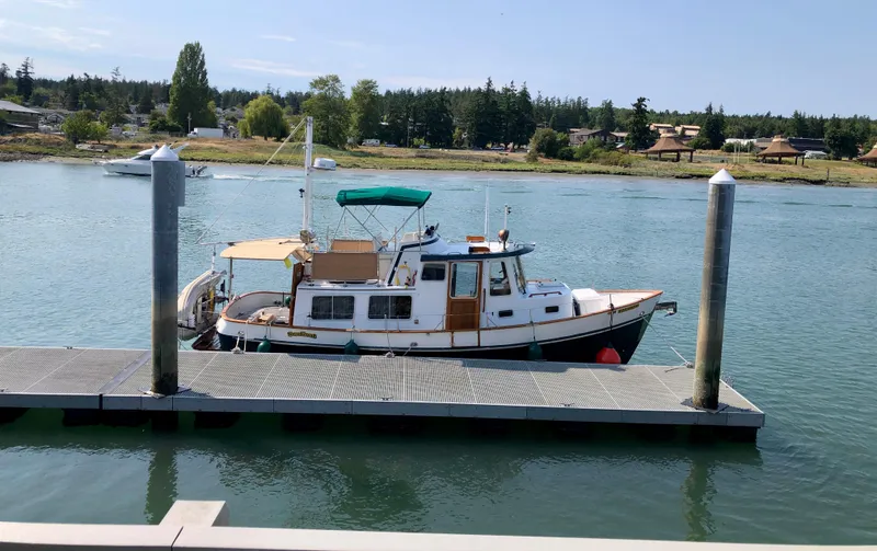 Slide: The Image of 1989 Eagle 32 Trawler docked on calm water with scenic background. - 28