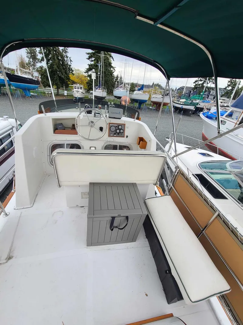 Slide: The Image of 1989 Eagle 32 Trawler cockpit with steering wheel, seating, and canopy in a marina setting. - 3