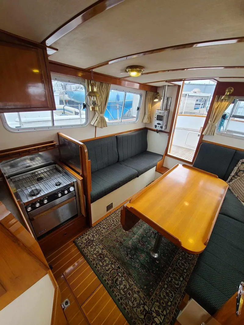 Slide: The Image of Interior of 1989 Eagle 32 Trawler with cozy seating, wooden table, and kitchen area. - 8