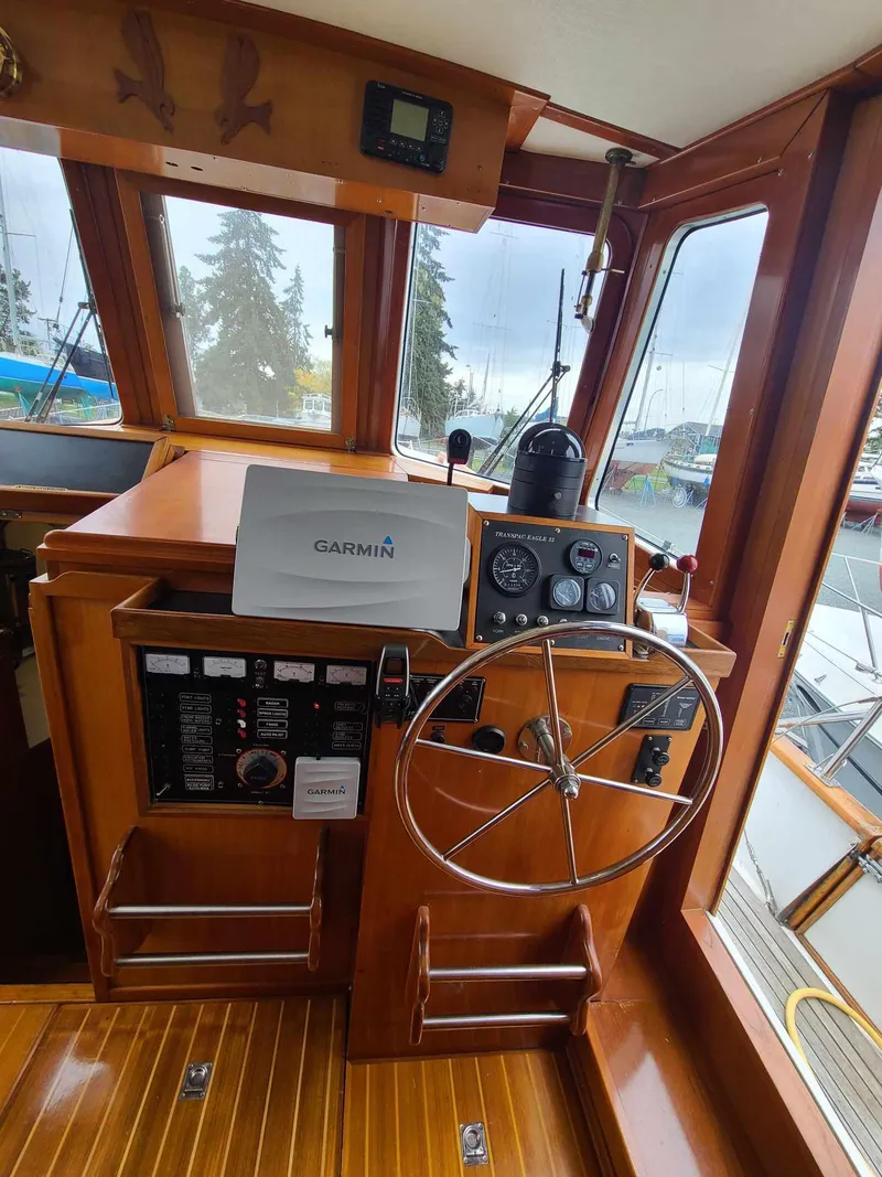 Slide: The Image of 1989 Eagle 32 Trawler helm with Garmin navigation, wooden interior, and steering wheel. - 9