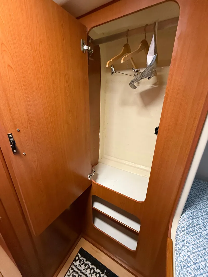 Slide: The Image of Wooden closet interior on a 2010 Leopard 38 yacht, featuring hangers and shelves. - 7