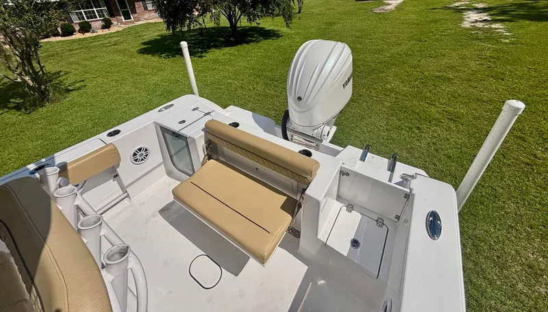 Slide: The Image of 2024 Sportsman Open 232 Center Console boat interior with seating and motor, on grass. - 3