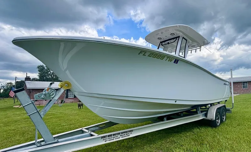 Slide: The Image of 2024 Sportsman Open 232 Center Console boat on trailer, parked on grass under cloudy sky. - 7