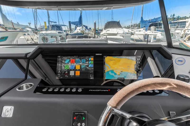 Slide: The Image of 2021 Axopar 37 XC BRABUS helm with navigation display, docked among sailboats. - 13