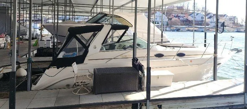 Slide: The Image of 2000 Rinker 340 Fiesta Vee docked under a covered marina with scenic waterfront view. - 12