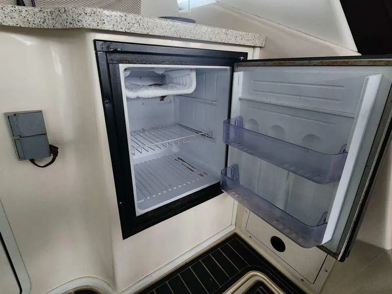 Slide: The Image of Open refrigerator inside a 2000 Rinker 340 Fiesta Vee boat, showing empty shelves. - 18