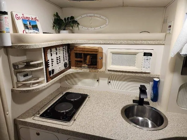 Slide: The Image of Compact kitchen area in a 2000 Rinker 340 Fiesta Vee boat with stove, sink, and microwave. - 33