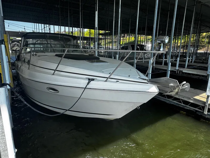 Slide: The Image of 2000 Rinker 340 Fiesta Vee boat docked in a marina under a covered structure. - 4