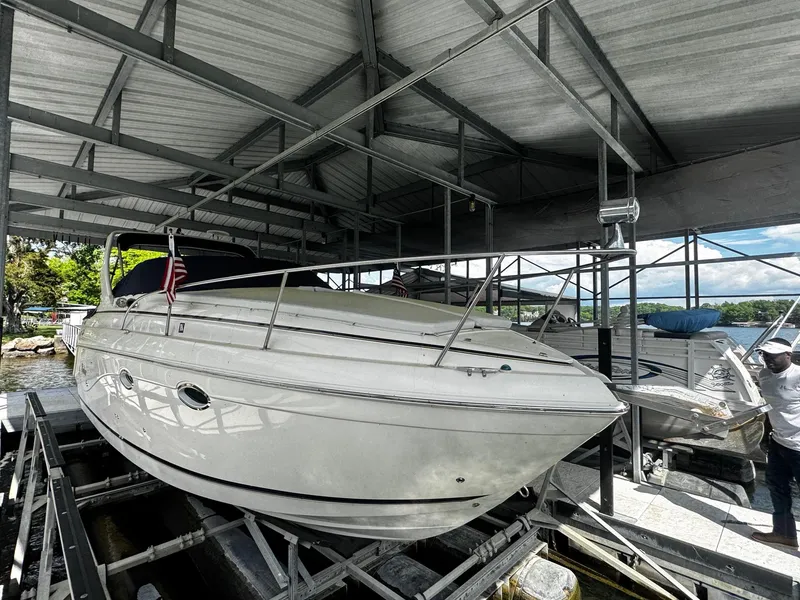 The Image of 2003 Rinker 270 Express Cruiser docked under a metal canopy. - 0