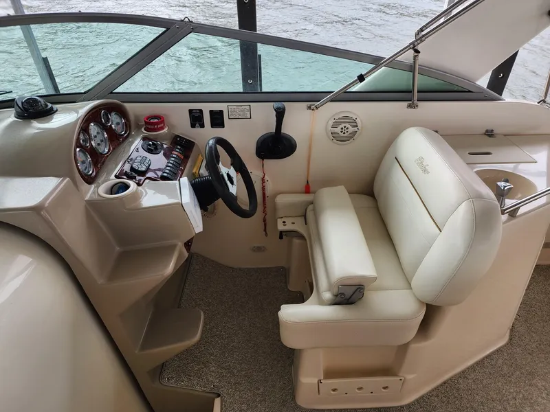 Slide: The Image of 2003 Rinker 270 Express Cruiser helm with beige seating and control panel. - 13