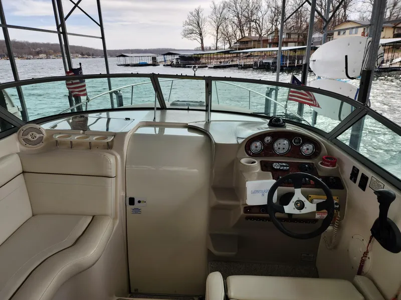 Slide: The Image of 2003 Rinker 270 Express Cruiser cockpit with steering wheel and dashboard, docked by a lake. - 15