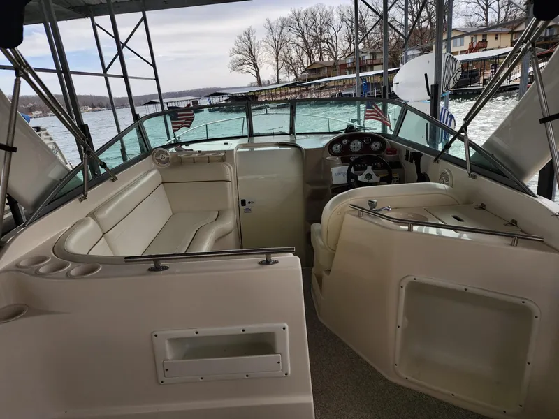 Slide: The Image of 2003 Rinker 270 Express Cruiser interior with seating and steering, docked by a lake. - 18