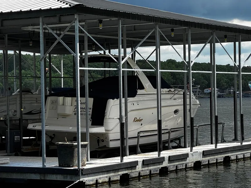Slide: The Image of 2003 Rinker 270 Express Cruiser docked under a metal canopy on a lake. - 2