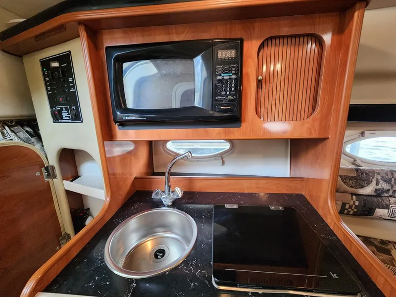 Slide: The Image of 2003 Rinker 270 Express Cruiser kitchen with microwave, sink, and stove. - 22