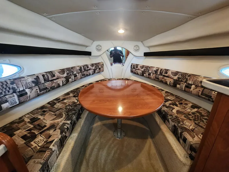 Slide: The Image of Interior of 2003 Rinker 270 Express Cruiser with patterned seating and wooden table. - 24