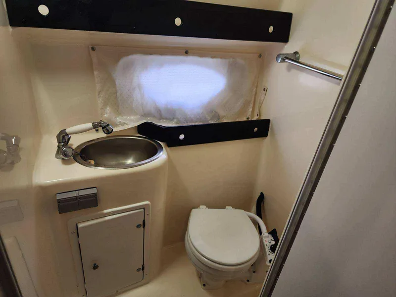 Slide: The Image of 2003 Rinker 270 Express Cruiser bathroom with sink, toilet, and window. - 27