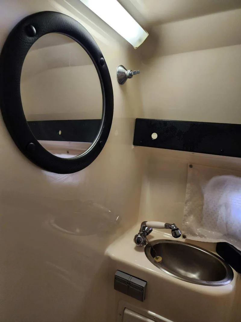 Slide: The Image of 2003 Rinker 270 Express Cruiser bathroom with sink and round mirror. - 28