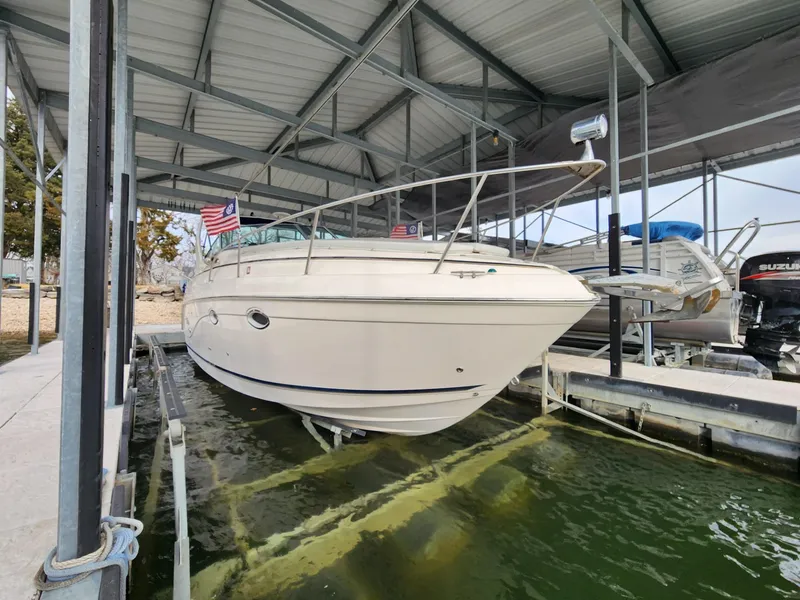 Slide: The Image of 2003 Rinker 270 Express Cruiser docked under a metal roof with American flags. - 3
