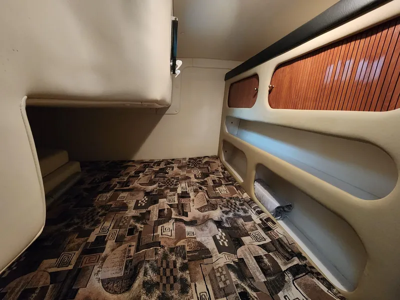 Slide: The Image of 2003 Rinker 270 Express Cruiser cabin interior with patterned carpet and wooden storage compartments. - 31