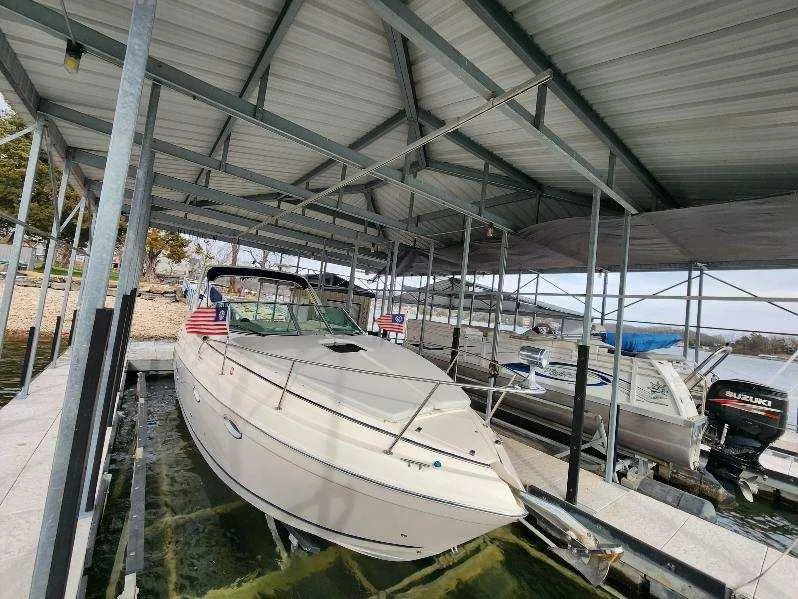 Slide: The Image of 2003 Rinker 270 Express Cruiser docked under a metal canopy at a marina. - 7