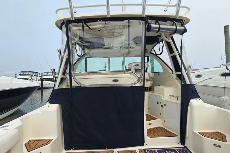 Slide: The Image of 2009 Pursuit OS 315 Offshore boat docked, featuring enclosed cockpit and seating area. - 13