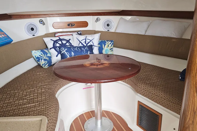 Slide: The Image of 2009 Pursuit OS 315 Offshore cabin with cozy seating and nautical-themed pillows. - 23