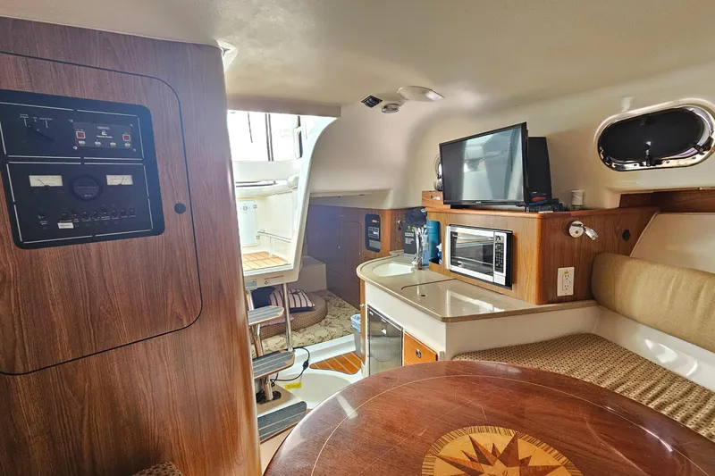 Slide: The Image of 2009 Pursuit OS 315 Offshore cabin interior with kitchenette, seating, and control panel. - 28