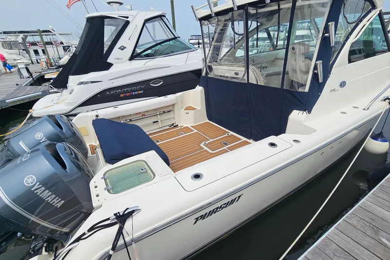 Slide: The Image of 2009 Pursuit OS 315 Offshore boat docked with Yamaha engines, featuring a spacious deck. - 5