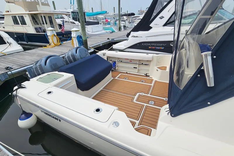 Slide: The Image of 2009 Pursuit OS 315 Offshore boat docked, featuring teak deck and twin outboard engines. - 6