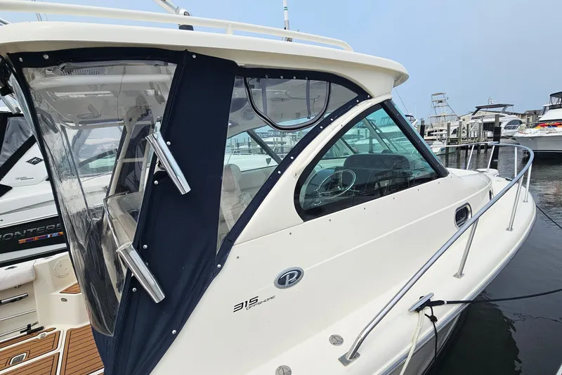 Slide: The Image of 2009 Pursuit OS 315 Offshore boat docked at marina, featuring sleek design and enclosed cabin. - 7