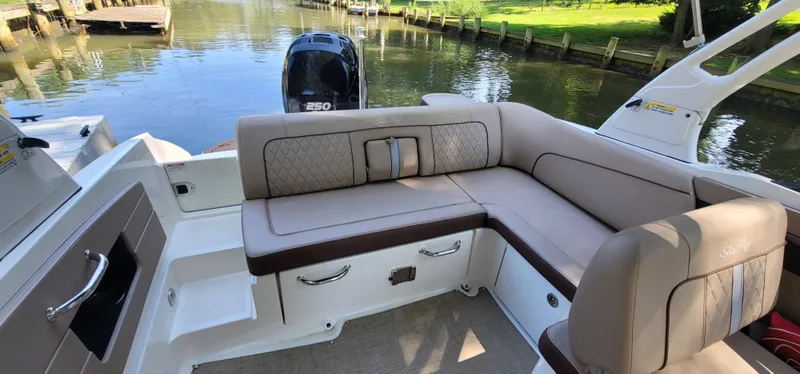 Slide: The Image of 2017 Sea Ray SDX 240 Outboard boat interior with plush seating and scenic water backdrop. - 12
