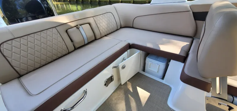 Slide: The Image of 2017 Sea Ray SDX 240 Outboard boat interior with beige leather seating and storage compartments. - 13