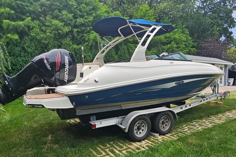 Slide: The Image of 2017 Sea Ray SDX 240 Outboard boat on trailer, surrounded by lush greenery. - 19