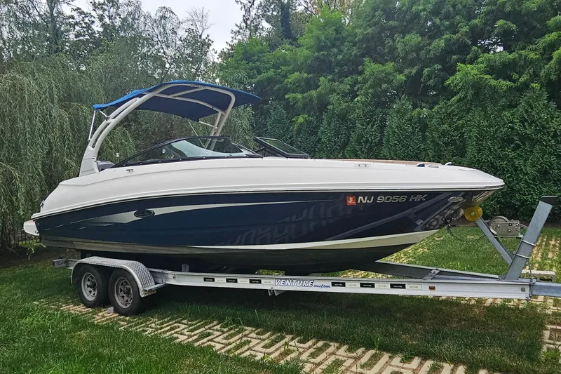 Slide: The Image of 2017 Sea Ray SDX 240 Outboard boat on trailer, surrounded by lush greenery. - 21