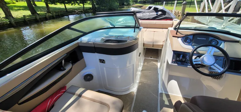 Slide: The Image of 2017 Sea Ray SDX 240 Outboard interior with steering wheel and seating, docked by a scenic canal. - 8