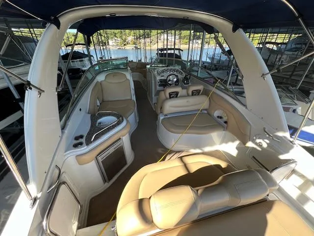 Slide: The Image of 2012 Crownline 325 SS boat interior with seating, helm, and canopy in marina setting. - 10