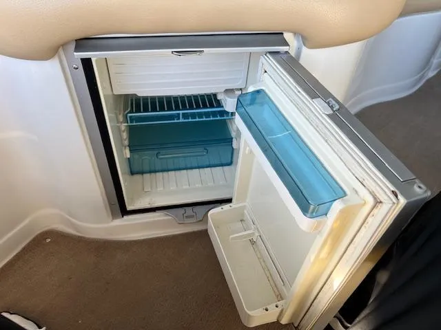 Slide: The Image of Open mini fridge inside 2012 Crownline 325 SS boat, showing interior shelves and door compartments. - 23