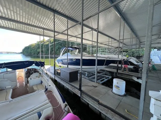 Slide: The Image of 2012 Crownline 325 SS boat docked in a covered marina with scenic lake view. - 3