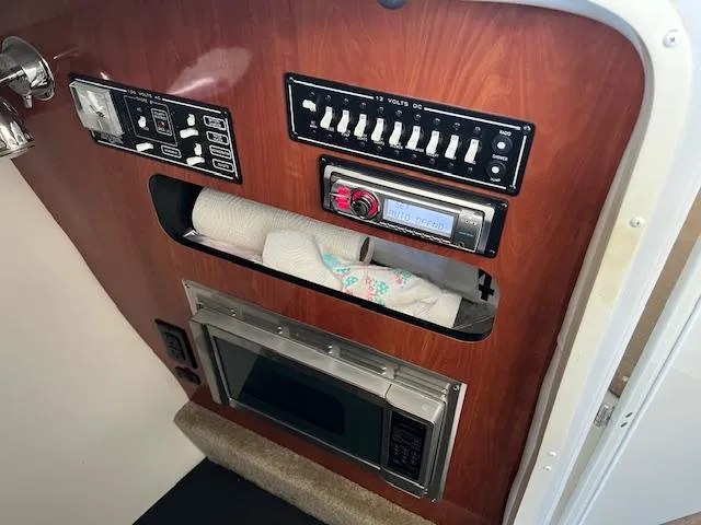 Slide: The Image of Control panel and microwave in 2012 Crownline 325 SS boat interior. - 39