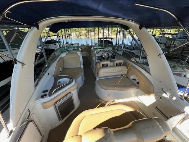Slide: The Image of 2012 Crownline 325 SS boat interior with seating, helm, and canopy in marina setting. - 9