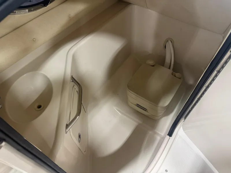 Slide: The Image of 2005 Sea Ray 240 Sundeck interior with portable toilet and sink. - 14