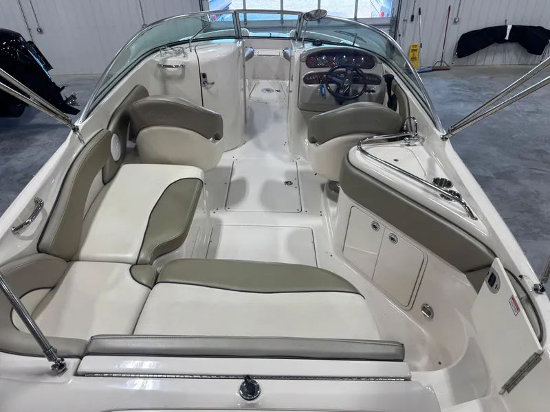 Slide: The Image of 2005 Sea Ray 240 Sundeck interior with beige seating and steering console. - 6