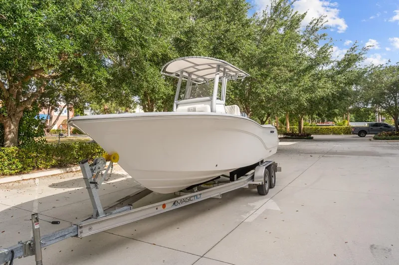 Slide: The Image of 2025 Sea Fox 228 Commander boat on trailer, parked outdoors with trees in background. - 2