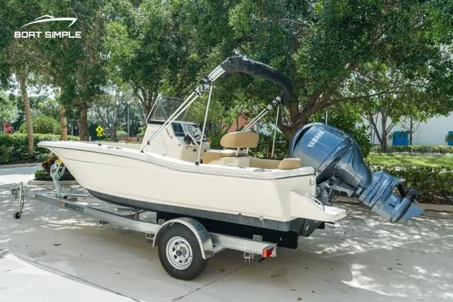 Slide: The Image of 2024 Scout 195 Sportfish boat on trailer, parked outdoors, featuring Yamaha outboard motor. - 1