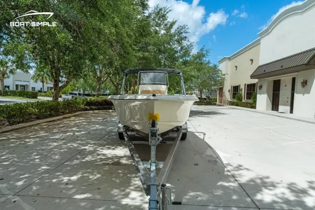Slide: The Image of 2024 Scout 195 Sportfish boat on trailer, parked outdoors under clear blue sky. - 3